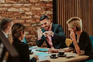 Happy businesspeople smiling cheerfully during a meeting in a coffee shop. Group of successful business professionals working as a team in a multicultural workplace. photo