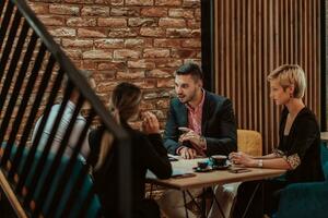 Happy businesspeople smiling cheerfully during a meeting in a coffee shop. Group of successful business professionals working as a team in a multicultural workplace. photo