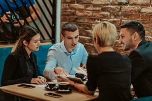 contento gente de negocios sonriente alegremente durante un reunión en un café tienda. grupo de exitoso negocio profesionales trabajando como un equipo en un multicultural lugar de trabajo. foto