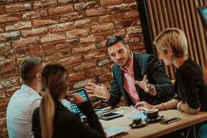 Happy businesspeople smiling cheerfully during a meeting in a coffee shop. Group of successful business professionals working as a team in a multicultural workplace. photo