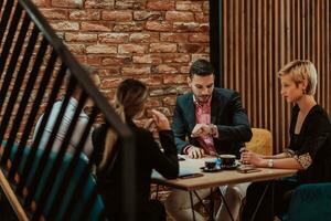 Happy businesspeople smiling cheerfully during a meeting in a coffee shop. Group of successful business professionals working as a team in a multicultural workplace. photo