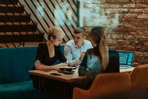 Happy businesspeople smiling cheerfully during a meeting in a coffee shop. Group of successful business professionals working as a team in a multicultural workplace. photo