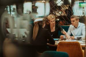 contento gente de negocios sonriente alegremente durante un reunión en un café tienda. grupo de exitoso negocio profesionales trabajando como un equipo en un multicultural lugar de trabajo. foto