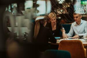 Happy businesspeople smiling cheerfully during a meeting in a coffee shop. Group of successful business professionals working as a team in a multicultural workplace. photo