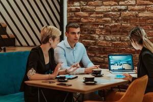 Happy businesspeople smiling cheerfully during a meeting in a coffee shop. Group of successful business professionals working as a team in a multicultural workplace. photo