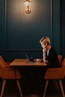 Businesswoman sitting in a cafe while focused on working on a laptop and participating in an online meetings. Selective focus. High quality photo