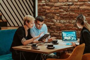 Happy businesspeople smiling cheerfully during a meeting in a coffee shop. Group of successful business professionals working as a team in a multicultural workplace. photo