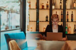 Businesswoman sitting in a cafe while focused on working on a laptop and participating in an online meetings. Selective focus. High quality photo