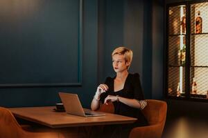 Businesswoman sitting in a cafe while focused on working on a laptop and participating in an online meetings. Selective focus. High quality photo