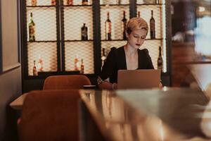 Businesswoman sitting in a cafe while focused on working on a laptop and participating in an online meetings. Selective focus. High quality photo