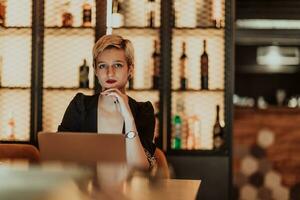 mujer de negocios sentado en un café mientras enfocado en trabajando en un ordenador portátil y participativo en un en línea reuniones selectivo enfocar. alto calidad foto