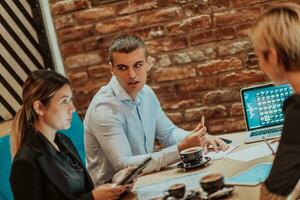 Happy businesspeople smiling cheerfully during a meeting in a coffee shop. Group of successful business professionals working as a team in a multicultural workplace. photo