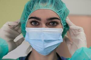 The female animal surgeon or veterinarian puts on a medical face mask. Doctor is preparing for surgery in the operation room. Medicine and healthcare photo