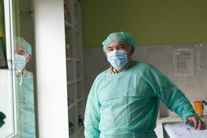 Mature confident doctor standing in front of surgery room - focus on the face photo