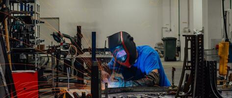 Professional Heavy Industry Welder Working Inside factory, Wears Helmet and Starts Welding. Selective Focus photo