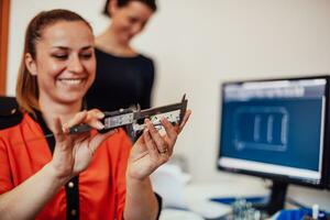 Within the heavy industry, a factory industrial engineer measures with a caliper and on a personal computer Designs a 3D model photo