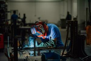 Professional Heavy Industry Welder Working Inside factory, Wears Helmet and Starts Welding. Selective Focus photo