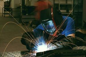 Professional Heavy Industry Welder Working Inside factory, Wears Helmet and Starts Welding. Selective Focus photo