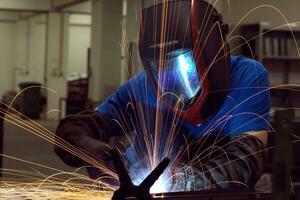 Professional Heavy Industry Welder Working Inside factory, Wears Helmet and Starts Welding. Selective Focus photo