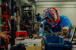 soldador profesional de la industria pesada que trabaja dentro de la fábrica, usa casco y comienza a soldar. enfoque selectivo foto