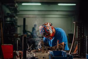 soldador profesional de la industria pesada que trabaja dentro de la fábrica, usa casco y comienza a soldar. enfoque selectivo foto