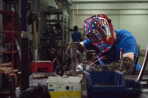 Professional Heavy Industry Welder Working Inside factory, Wears Helmet and Starts Welding. Selective Focus photo