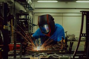 Professional Heavy Industry Welder Working Inside factory, Wears Helmet and Starts Welding. Selective Focus photo