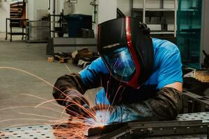 Professional Heavy Industry Welder Working Inside factory, Wears Helmet and Starts Welding. Selective Focus photo