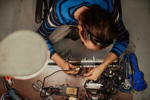 Industrial worker man soldering cables of manufacturing equipment in a factory. Selective focus photo