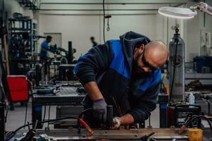 Industrial worker man soldering cables of manufacturing equipment in a factory. Selective focus photo