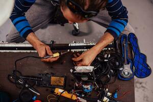 Industrial worker man soldering cables of manufacturing equipment in a factory. Selective focus photo