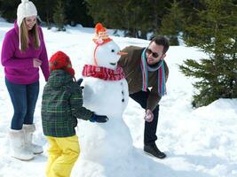 familia feliz haciendo muñeco de nieve foto