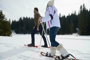couple having fun and walking in snow shoes photo