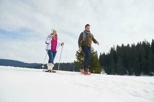 pareja divirtiéndose y caminando con raquetas de nieve foto