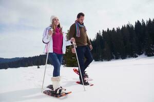 pareja divirtiéndose y caminando con raquetas de nieve foto