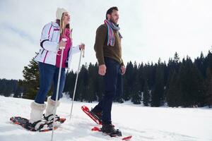 couple having fun and walking in snow shoes photo