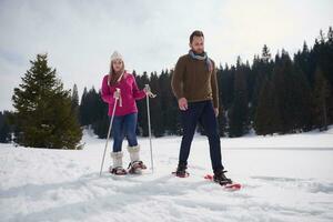 couple having fun and walking in snow shoes photo