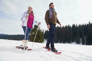 pareja divirtiéndose y caminando con raquetas de nieve foto