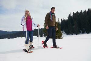 pareja divirtiéndose y caminando con raquetas de nieve foto