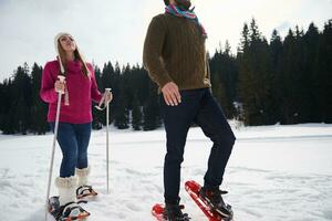 couple having fun and walking in snow shoes photo