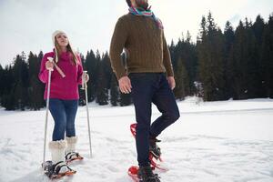 couple having fun and walking in snow shoes photo