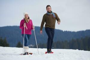 couple having fun and walking in snow shoes photo