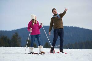 couple having fun and walking in snow shoes photo