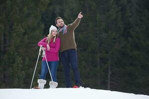 pareja divirtiéndose y caminando con raquetas de nieve foto