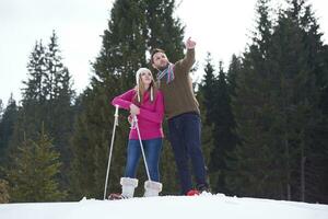 pareja divirtiéndose y caminando con raquetas de nieve foto