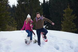 pareja divirtiéndose y caminando con raquetas de nieve foto