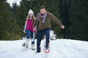 couple having fun and walking in snow shoes photo