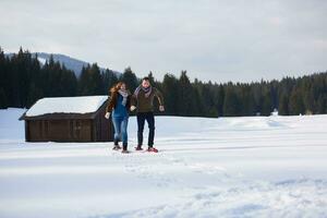 pareja divirtiéndose y caminando con raquetas de nieve foto