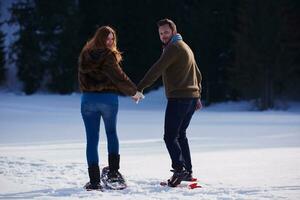 pareja divirtiéndose y caminando con raquetas de nieve foto