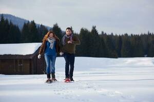 pareja divirtiéndose y caminando con raquetas de nieve foto